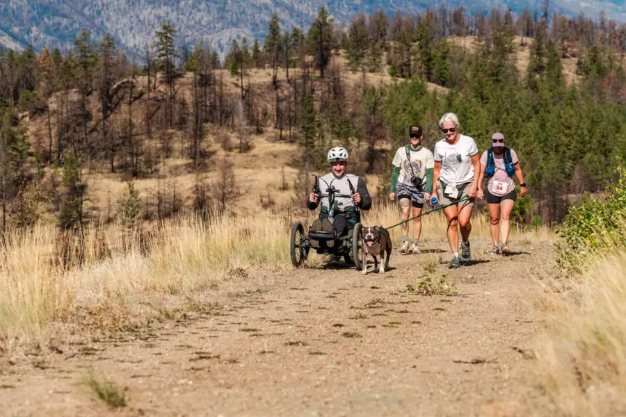 A handcyclist and walkers with a dog on the trail